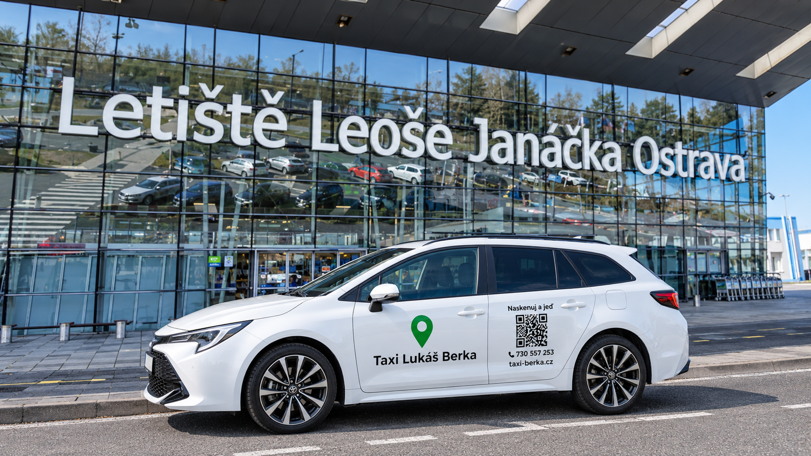 Bílé taxi stojí před moderní budovou s velkým nápisem Letiště Leoše Janáčka Ostrava.